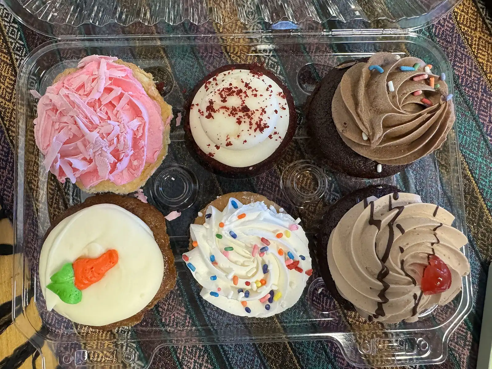 Six frosted cupcakes in a clear bakery box. The photo was not taken in Mooresville.