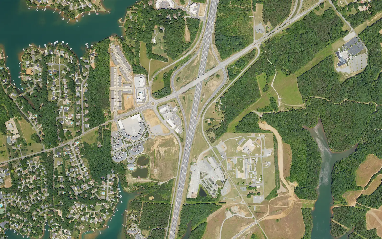 Aerial view of I-77 at Exit 31, Langtree Road, with new buildings beside the interchange and Lake Norman coves and lakeside neighborhoods to the west
