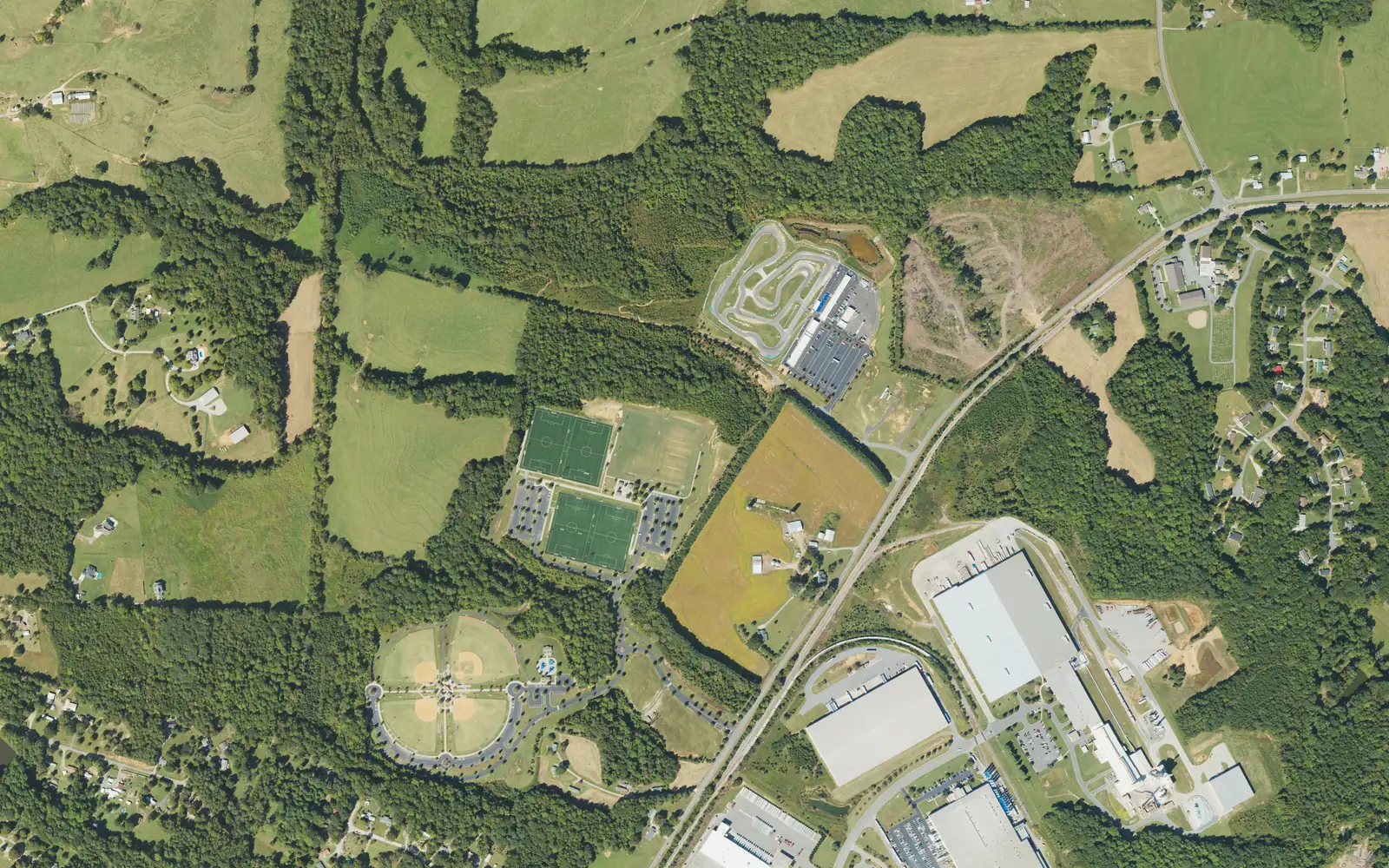 Aerial view of Mazeppa Park's ballfields and soccer fields off Mazeppa Road in northeast Mooresville, with farmland to the north and industrial buildings to the southeast