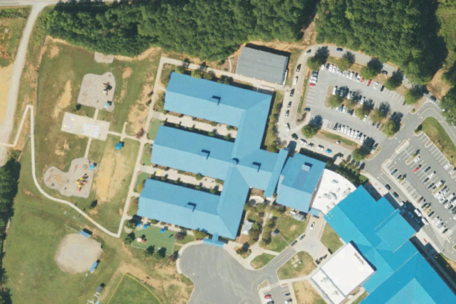 Woodland Heights Elementary School's blue-roofed classroom wings and playgrounds on Forest Lake Boulevard in Mooresville, seen from the air